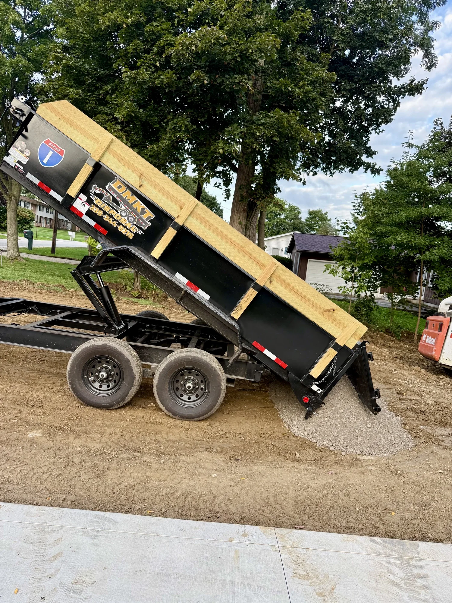 DMKT Disposal dump trailer with raised bed finishing a home cleanout in a Northeast Ohio driveway