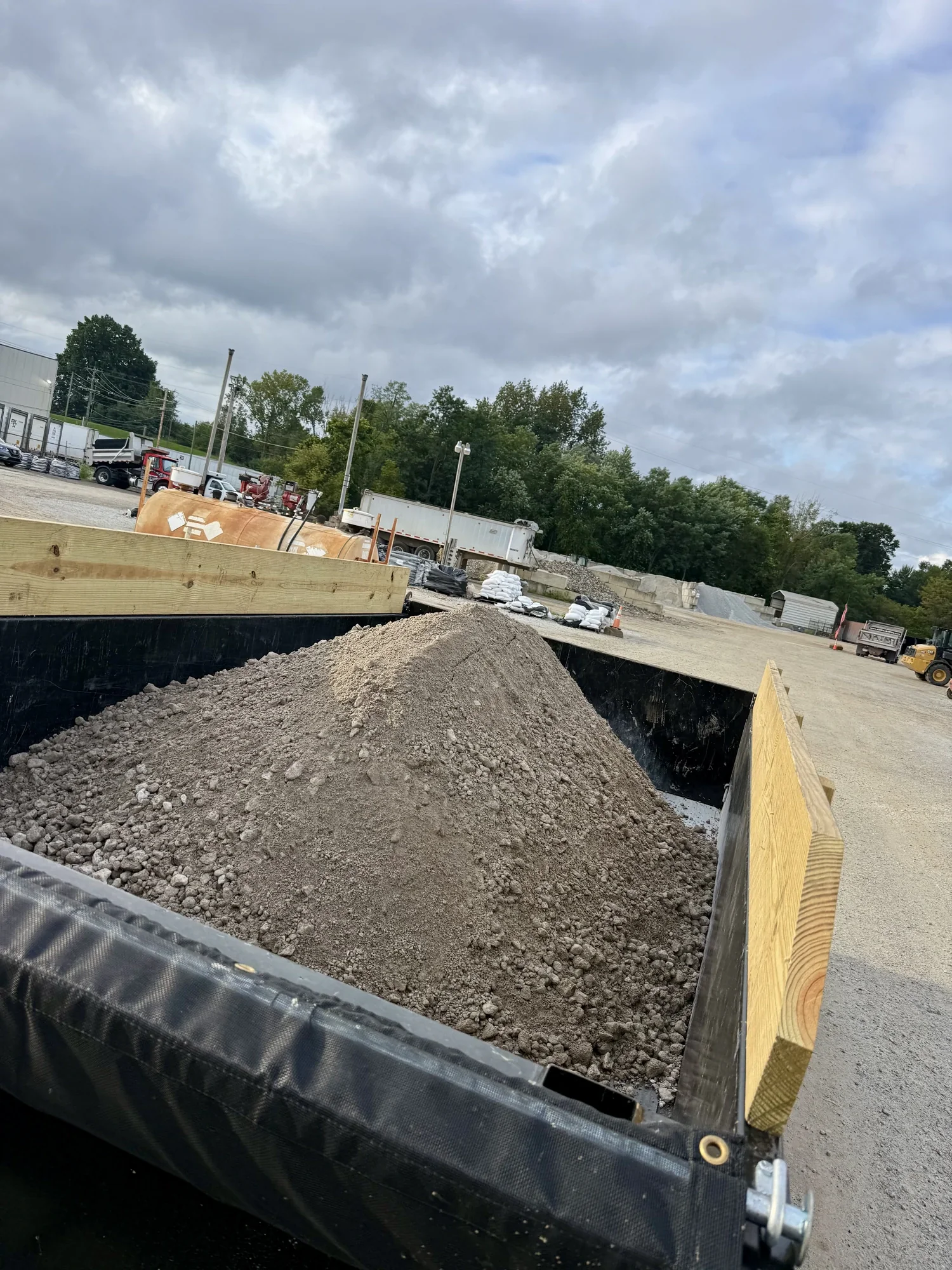 DMKT Disposal dump trailer loaded with gravel and material at a supply yard