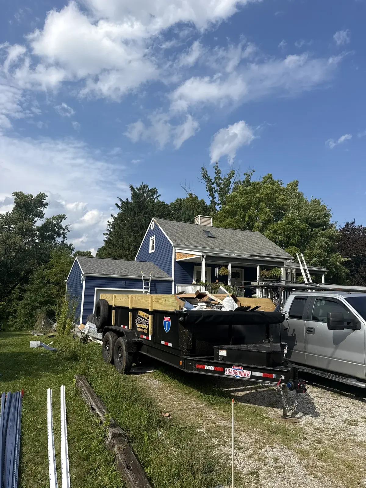 DMKT Disposal trailer loaded with junk hitched to a pickup truck at a Northeast Ohio home