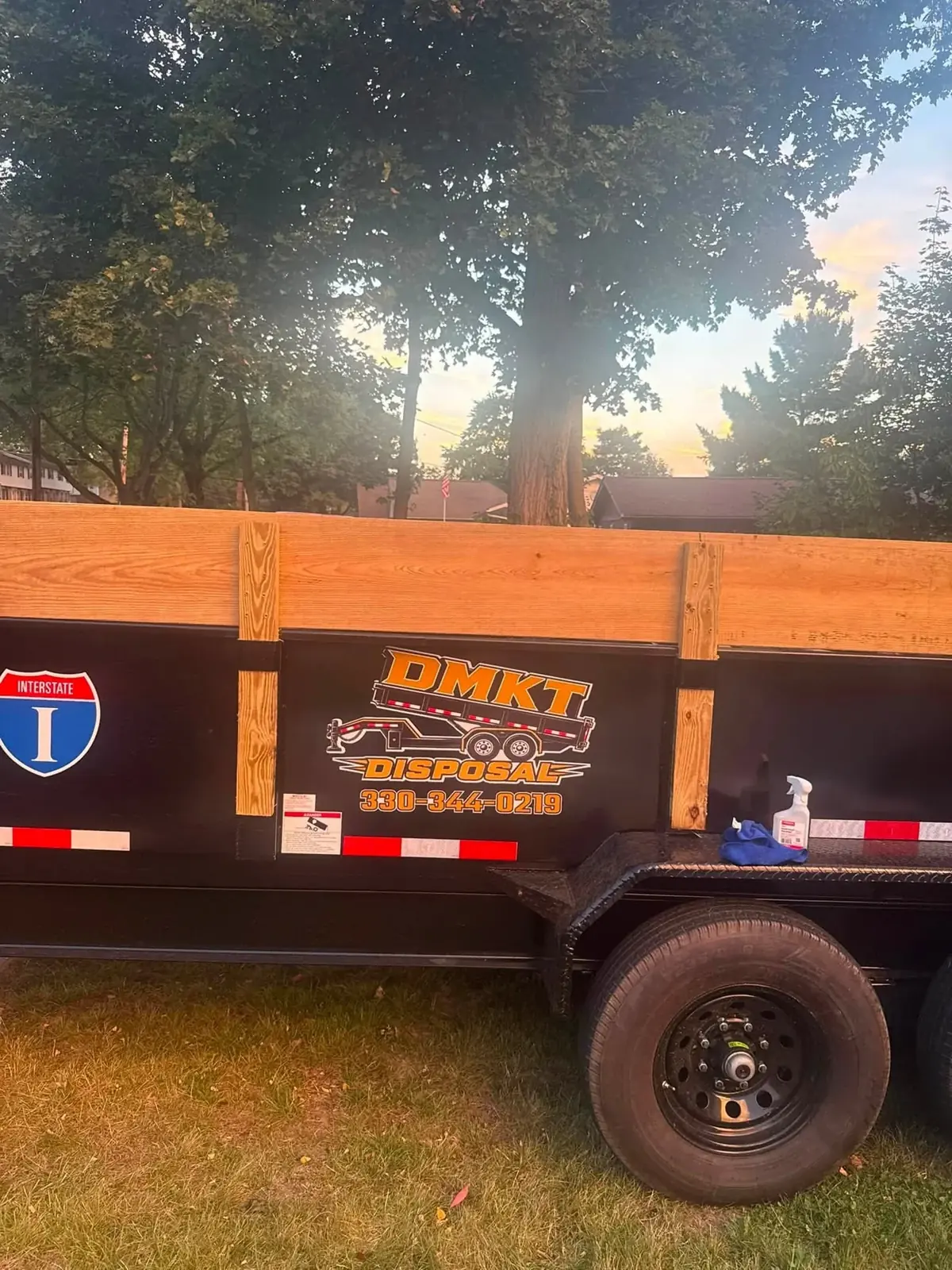 Close-up of the DMKT Disposal logo on the side of the black dump trailer